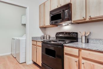 A kitchen with a black stove and wooden cabinets.
